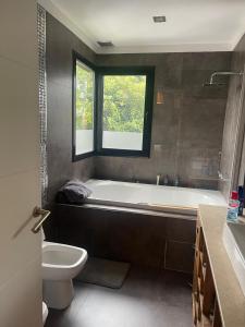 a bathroom with a tub and a toilet and a window at Punta Chica - Alojamiento Premium in Victoria