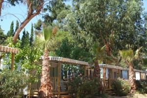 una cabina nel bosco con alberi e fiori di Camping de la Baie a Cavalaire-sur-Mer