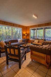 a living room with couches and tables and windows at Cabaña en el bosque de Llanos del Castor in Ushuaia