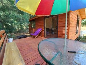 a table with a colorful umbrella on a wooden deck at Entre Aromos in Lago Ranco