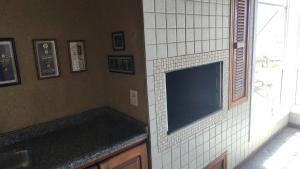 Una pared alicatada con un televisor en un baño en Apto Torres com vista para o Mar, 3 suítes, sacada com churrasqueira, en Torres
