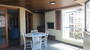 Un porche con una mesa y sillas y una ventana. en Apto Torres com vista para o Mar, 3 suítes, sacada com churrasqueira, en Torres