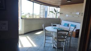 Una habitación con una mesa y sillas en un balcón. en Apto Torres com vista para o Mar, 3 suítes, sacada com churrasqueira, en Torres