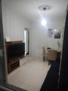 a living room with a flat screen tv and a table at Casa temporada regiao dos lagos São pedro in São Pedro da Aldeia