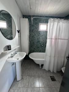 a bathroom with a sink and a tub and a mirror at La Celeste casa de playa in Las Grutas