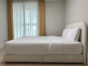 a white bed in a room with a window at The November Stay Guri Station in Guri