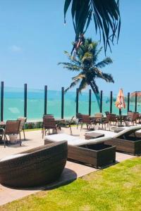 a patio with tables and chairs and a palm tree at Cobertura Duplex Pé na Areia 509 Tabatinga Residence in Conde +86 photos