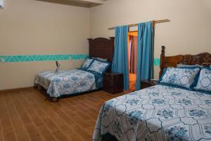 - une chambre avec un lit, un lit et une chaise dans l'établissement Casa Vacacional en calvillo, à El Rodeo