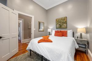 a bedroom with a large white bed with orange pillows at No Car Needed King Bed Balcony Abercorn And York-2 in Savannah