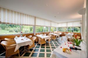 un ristorante con tavoli e sedie bianchi e finestre di Bad Schauenburg a Liestal