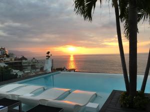 a swimming pool with a sunset over the ocean at DTerrace Luxe 2bd 2ba Romantic Zone Los Muertos Beach and Pier in Puerto Vallarta