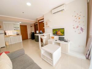 a living room with a couch and a tv on a wall at Homey Designed 3BR at Gateway Pasteur Apartment By Travelio in Bandung