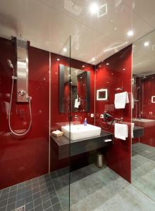 La salle de bains rouge est pourvue d'un lavabo et d'une douche. dans l'établissement Landgut Ramshof, à Willich