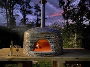 Un horno al aire libre sobre una mesa con una copa de vino. en Little Corner Farm, en Broke
