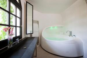 a white bath tub in a bathroom with windows at Domaine Saint Clair - Le Donjon in Étretat