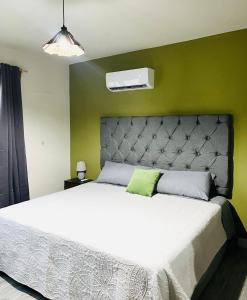 Un dormitorio con una cama blanca con una pared verde. en Departamento 2 Recamaras, en Ciudad Valles