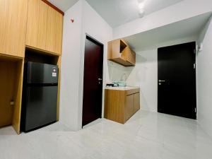 a kitchen with a black door and a refrigerator at Compact and Relaxing 2BR at Suncity Residence Apartment By Travelio in Sidoarjo