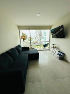 a living room with a black couch and a large window at Depa Nuevo Acapulco Diamante in Acapulco