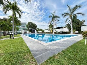 a swimming pool in a yard with palm trees at Depa Nuevo Acapulco Diamante in Acapulco