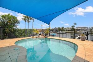 a large swimming pool with a blue umbrella at Canal living 3 bed or 1 bed with Pool in Redcliffe