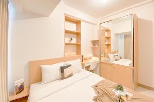 a bedroom with a white bed and a mirror at Good and Cozy Stay 2BR Tokyo Riverside PIK 2 Apartment By Travelio in Tangerang