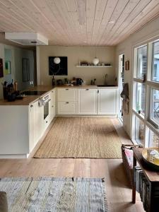 a large kitchen with white cabinets and a wooden floor at Idyllic Holiday Home In Ebeltofts Nature in Femmøller