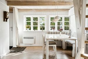 a kitchen with a white table and chairs and windows at Timber-Framed With Bright And Idyllic Garden in Juelsminde +30 photos