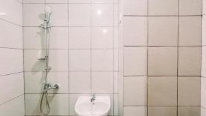 une salle de bain carrelée blanche avec toilettes et douche dans l'établissement Relaxing Studio No Kitchen Apartment Bandaraya Tallasa City Makassar By Travelio, à Paranglu