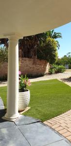a porch with a pot of flowers in the grass at Como Beach Apartments in Perth
