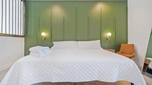 a bedroom with a large white bed with green walls at Chic Modern Condo in the Vibrant NuLu District in Louisville