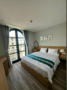 a bedroom with a large bed and a large window at Queen HT Phú Quốc in Phu Quoc
