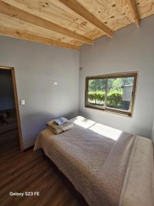 a bedroom with a large bed with a window at Cabañas don jose 1 in Pucón