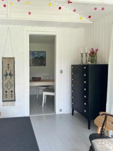a dining room with a table and a black dresser at Cosy Cabin Collection In Veddinge Bakker in Asnæs