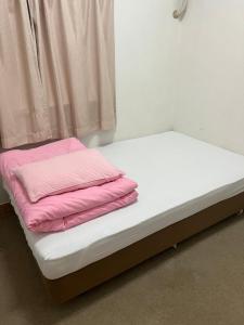 a bed with pink sheets on it in a room at 民宿ふがらっさ in Ishigaki Island