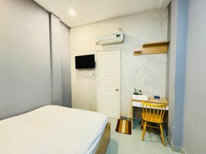 a small bedroom with a bed and a desk with a chair at Guest House Thiên Thanh in Phu Quoc