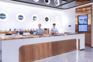 2 persone sedute al bancone nella hall di un hotel di Atour Light Hotel Shenzhen Guanlan Sany Cloud a Shenzhen