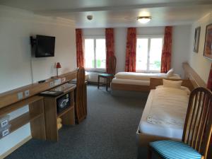 a hotel room with two beds and a tv at Gästehaus Sonne in Bütschwil