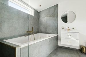 une salle de bain avec une baignoire et un miroir dans l'établissement Classic Seaside Hotel Feel In Ringkøbing Fjord, à Hemmet 28 autres photos