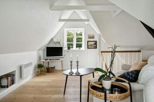 a living room with a couch and a tv at Timber-Framed With Bright And Idyllic Garden in Juelsminde
