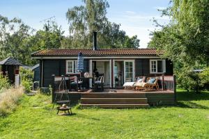 una pequeña casa con una gran terraza en el patio en Rustic Vibe In 60S House By Roskilde Fjord, en Jægerspris