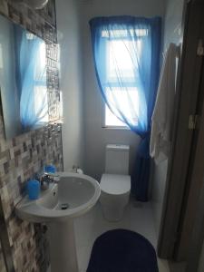uma casa de banho com um lavatório, um WC e uma janela. em Penthouse next to the beach em Marsaskala