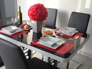 uma mesa de jantar com um vaso de rosas vermelhas em Penthouse next to the beach em Marsaskala