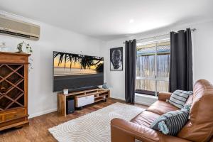 Una sala de estar con un sofá y un televisor en Family-Friendly Home with Private Pool and BBQ, en Buderim 11 fotos más