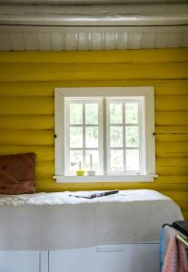 Habitación amarilla con cama y ventana en Log Cabin In The Heart Of Drammensmarka, en Drammen