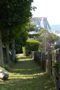 a stone wall with trees and a mountain in the background at Domaine Saint Clair - Le Donjon in Étretat