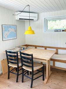 une table de salle à manger avec deux chaises et une lumière jaune dans l'établissement Summer House Charm Near Hårbølle Havn, à Askeby