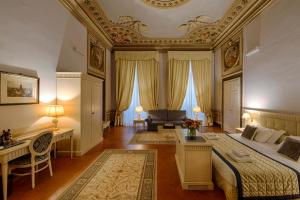 - une chambre avec un lit, un bureau et un canapé dans l'établissement Palazzo Guicciardini, à Florence