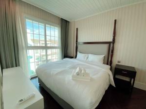 a bedroom with a bed with two white towels on it at Grand Florida Beach Front Pattaya in Na Jomtien