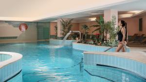 a woman is standing next to a swimming pool at Hotel Residence 3 Signori in Santa Caterina Valfurva