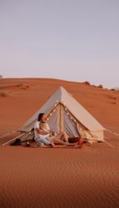 two people sitting inside a tent in the desert at Bidiyah Old Bedouin Wahaiba Desert CAMP in Badīyah